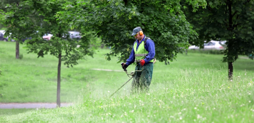 Man operating a weed eater in high grass